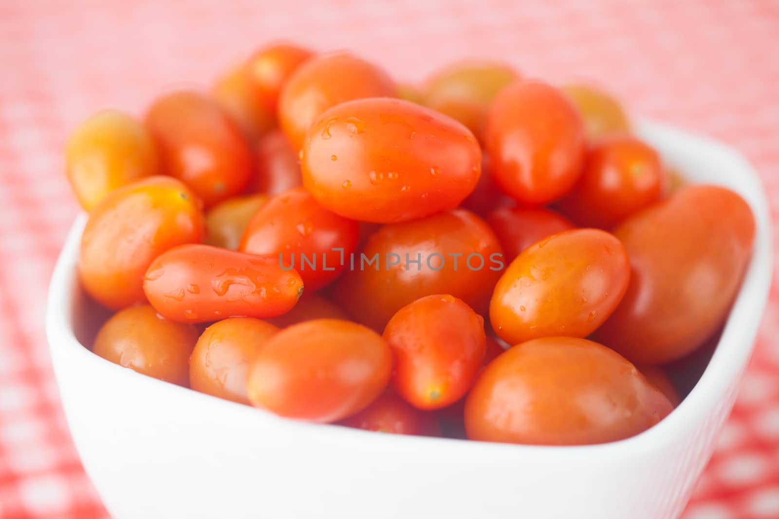 cherry tomatos in bowl on checkered fabric by jannyjus