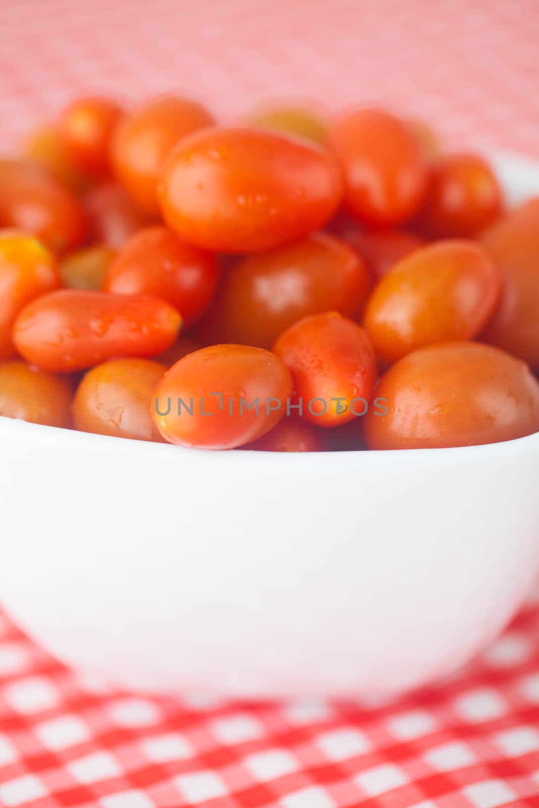 cherry tomatos in bowl on checkered fabric by jannyjus