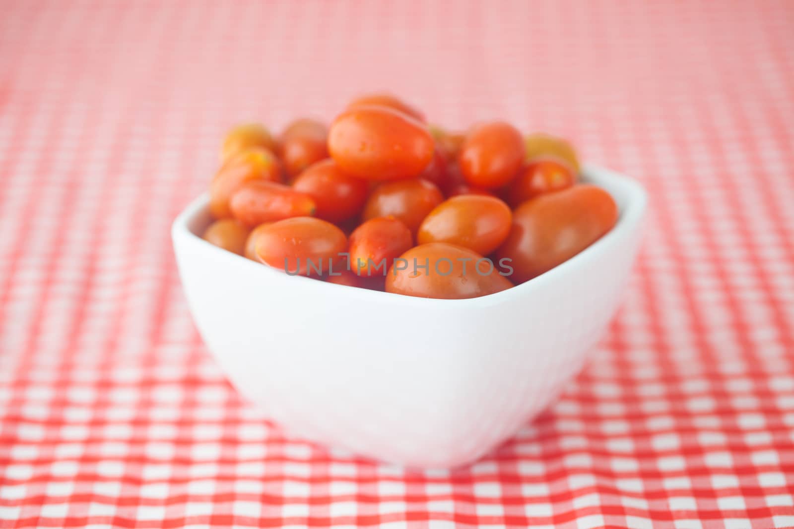 cherry tomatos in bowl on checkered fabric