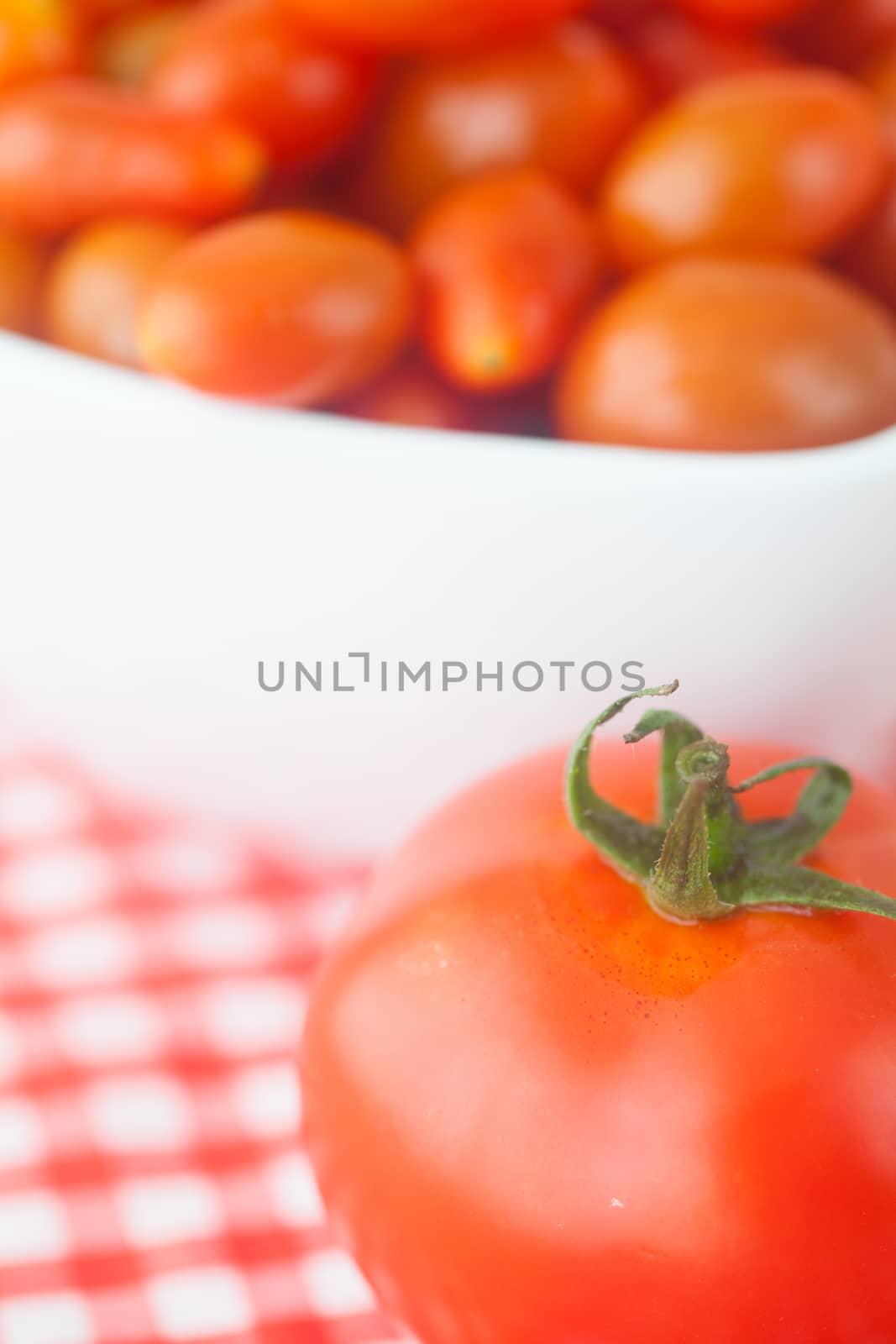 cherry tomatos and tomatos in bowl on checkered fabric