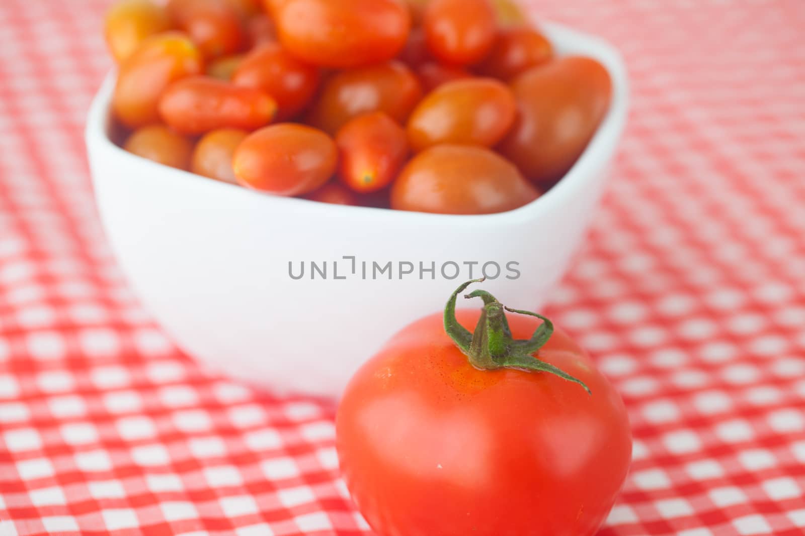 cherry tomatos and tomatos in bowl on checkered fabric