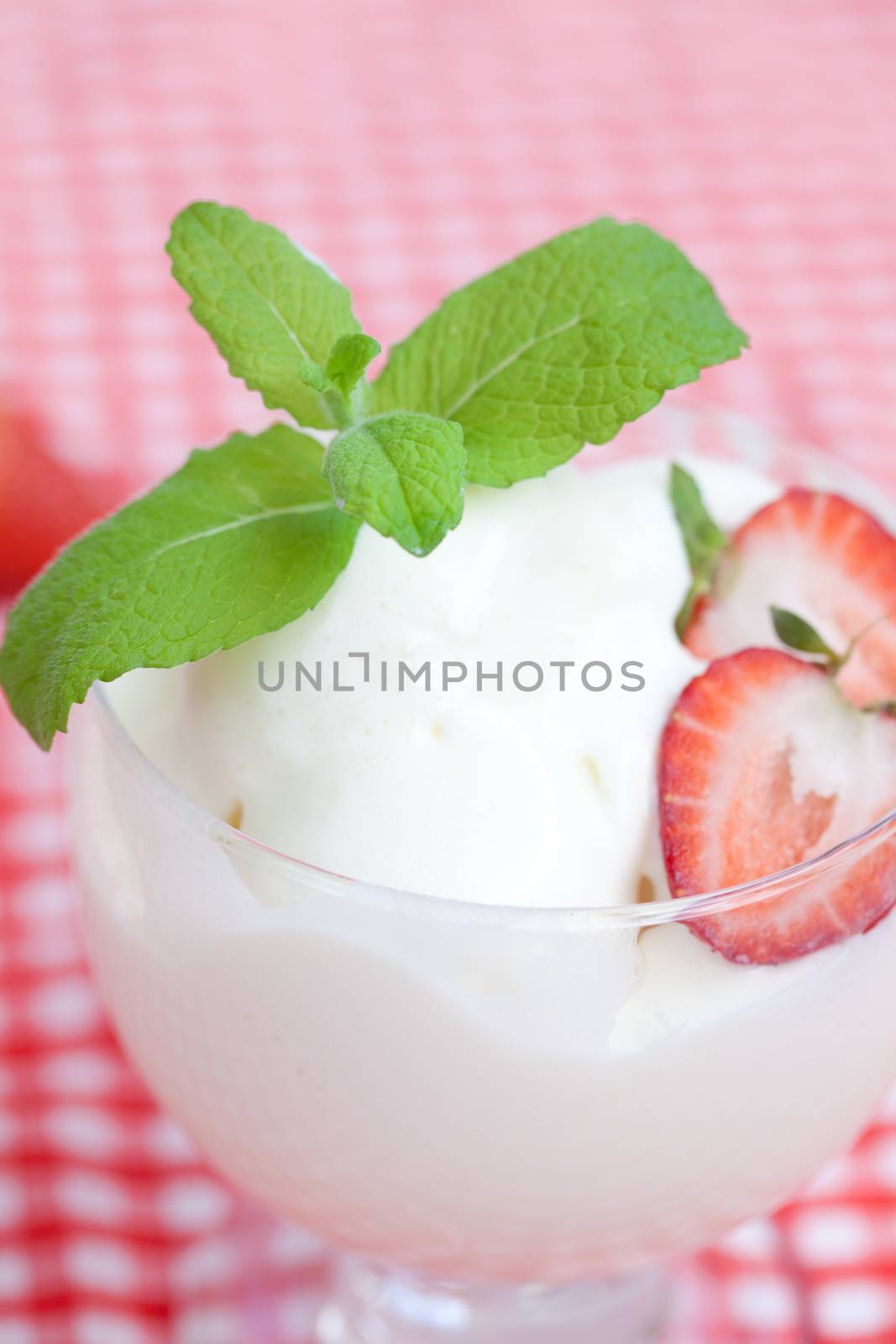 ice cream with mint in a glass bowl and strawberry on plaid fabric