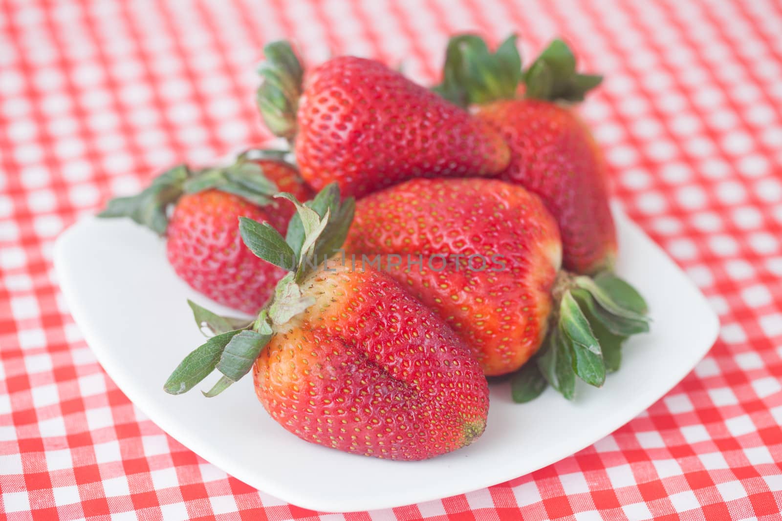 strawberries in bowl on checkered fabric