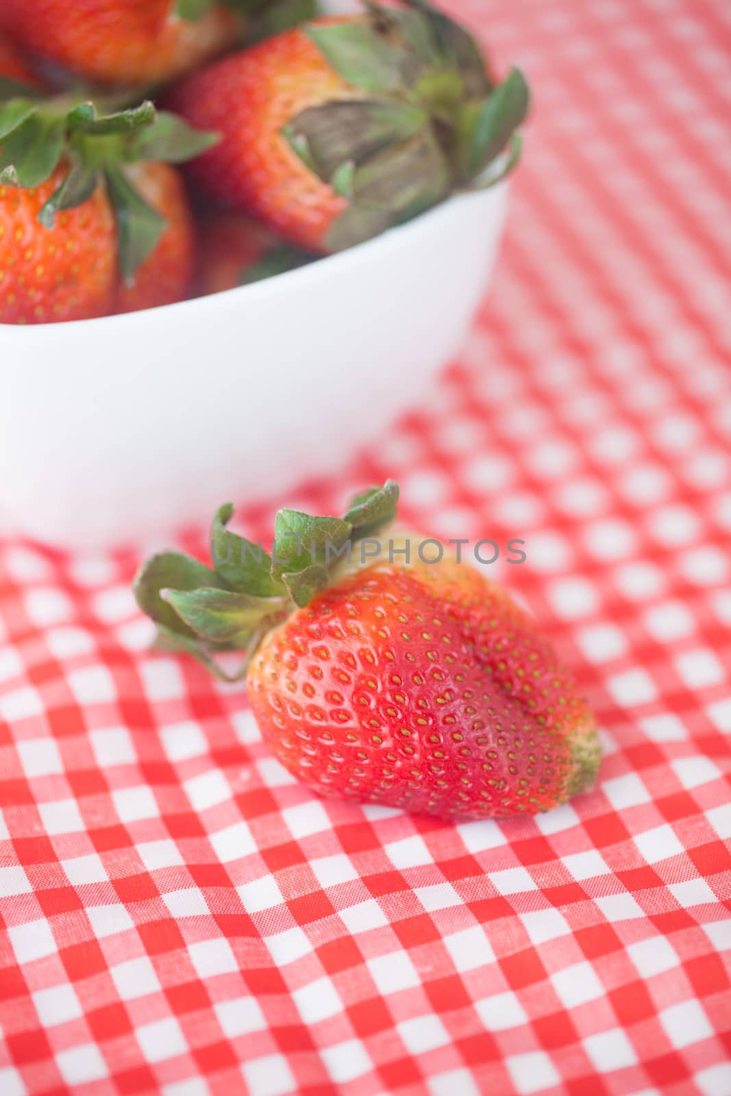 strawberries in bowl on checkered fabric