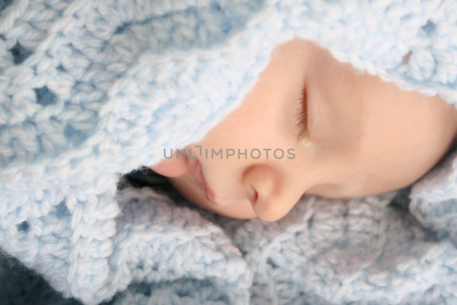 Sleeping baby boy wrapped in a wool blanket