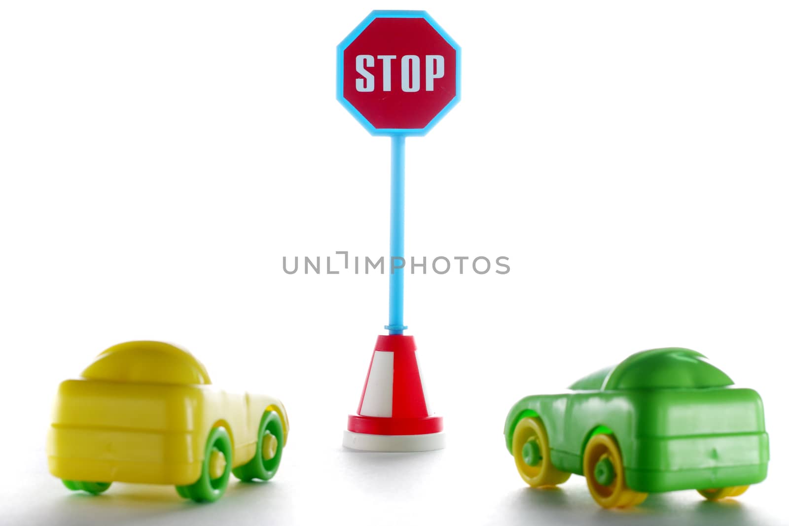 A couple cars behind stop road sign at white background