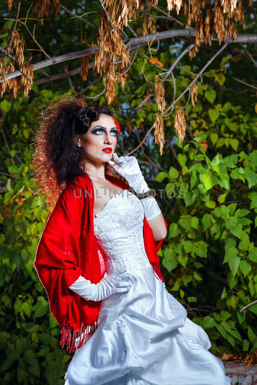 Attractive bride in a wedding dress with bright makeup, red shawl