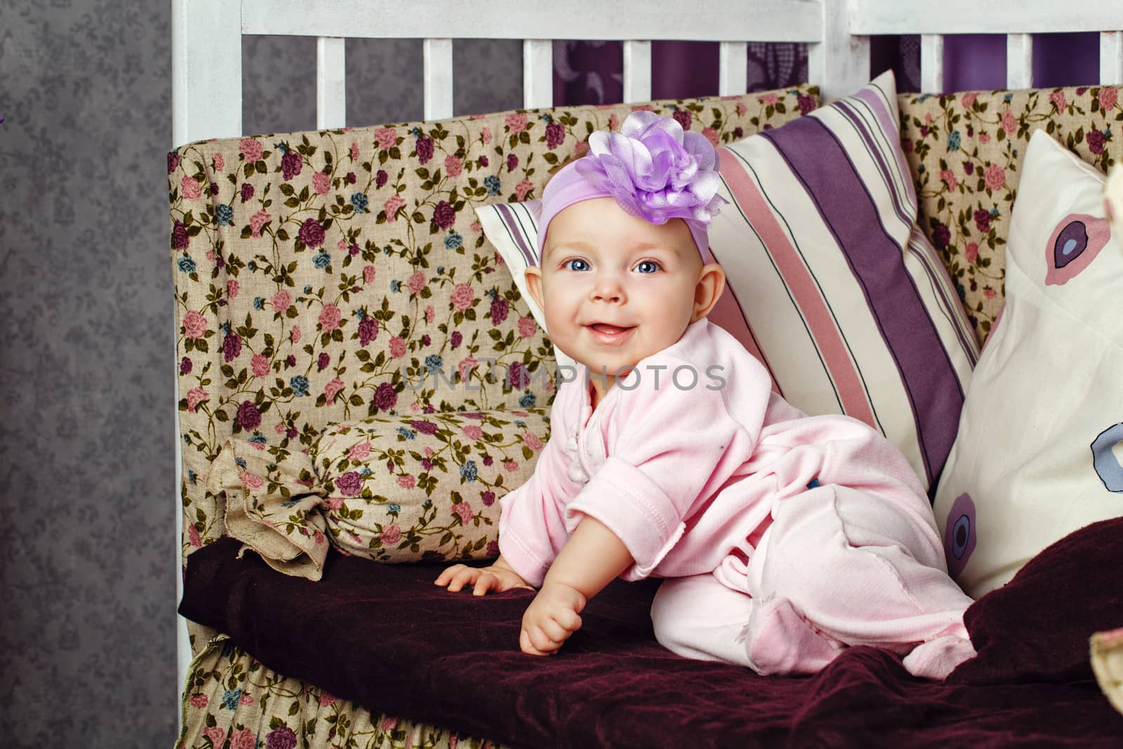 Little girl with bow on her head sitting on couch