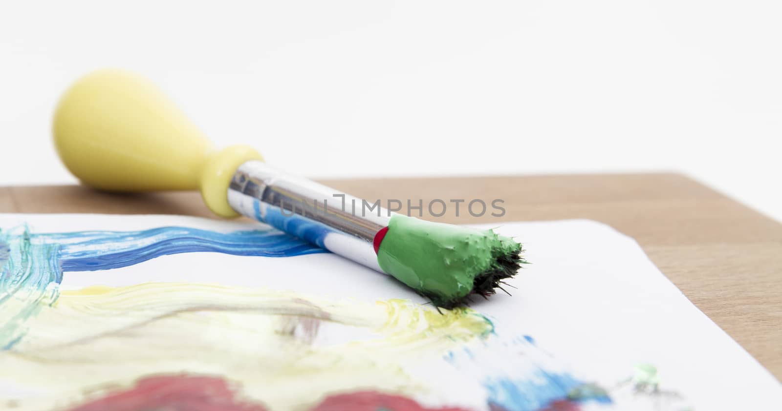 green paint with paint brush  and paper on wooden table