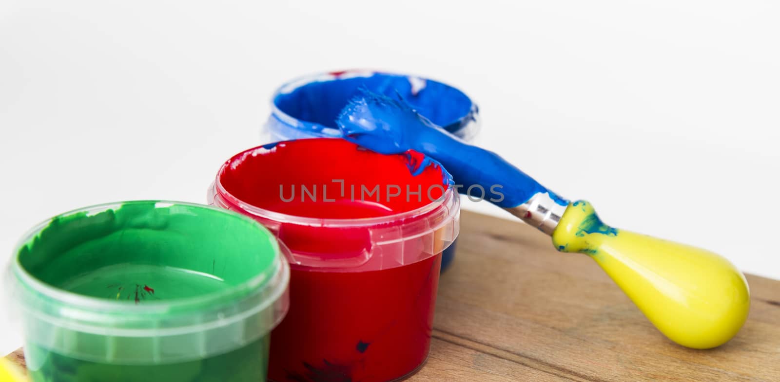 paint in small tubs with paint brush on wooden table