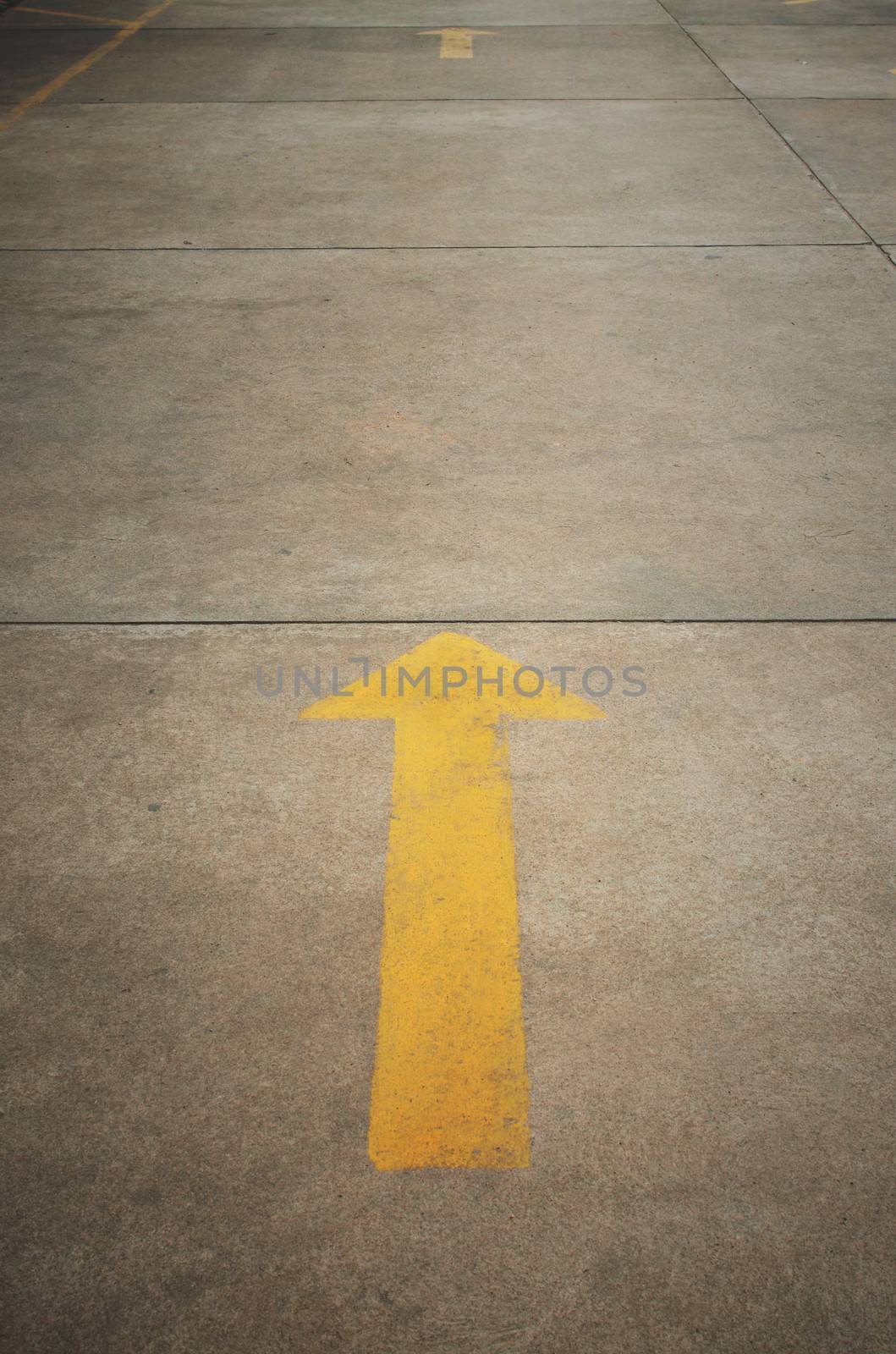 A yellow arrow on old concrete road