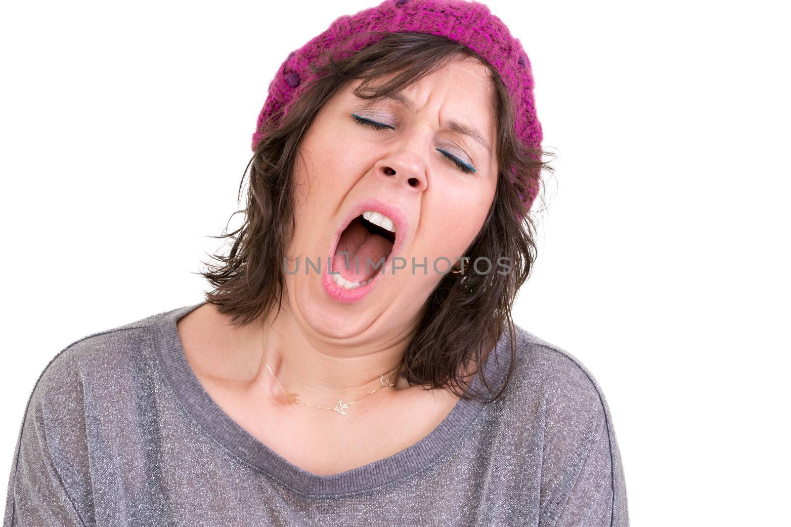 Exhausted or bored woman wearing a knitted beanie yawning with her mouth wide open and eyes shut isolated on white