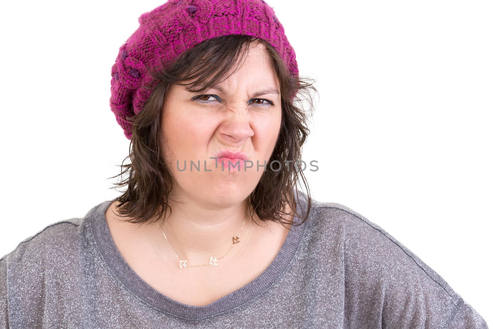 Disdainful woman in a purple knitted beanie screwing up her nose in disgust and dislike, head and shoulders isolated on white