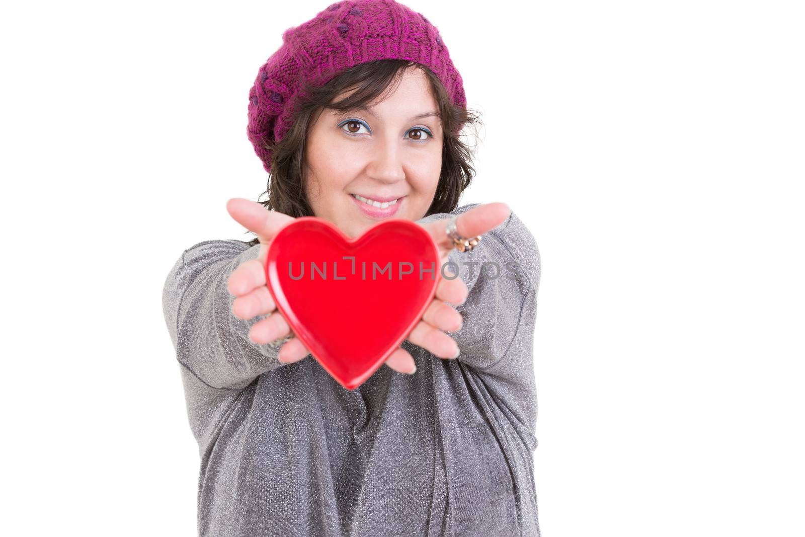 Happy woman holding out a red valentines heart for her sweetheart in her extended hands with a tender smile isolated on white