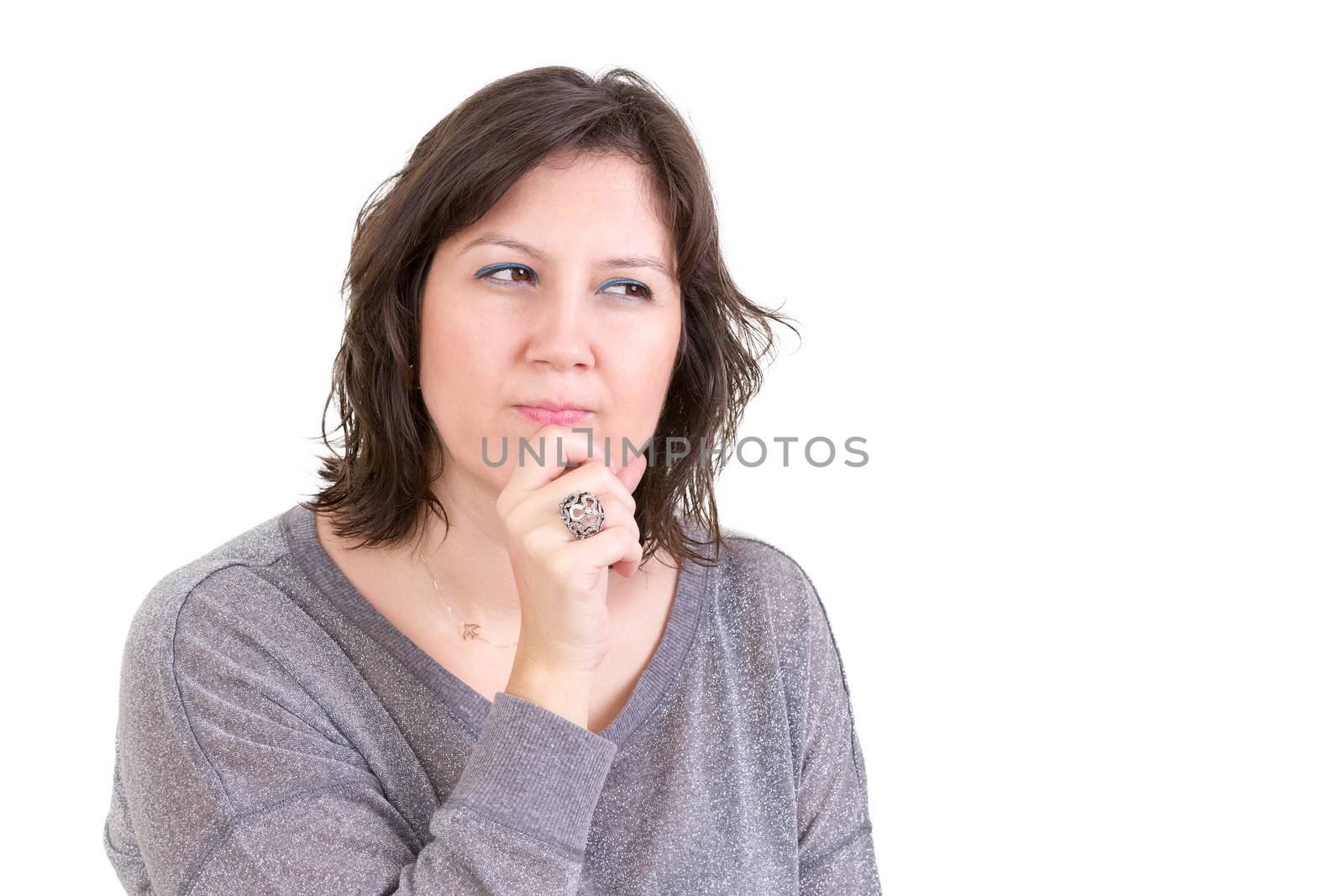 Woman with a calculating pensive look sitting with her hand to her chin as she plans and schemes for the future, isolated on white