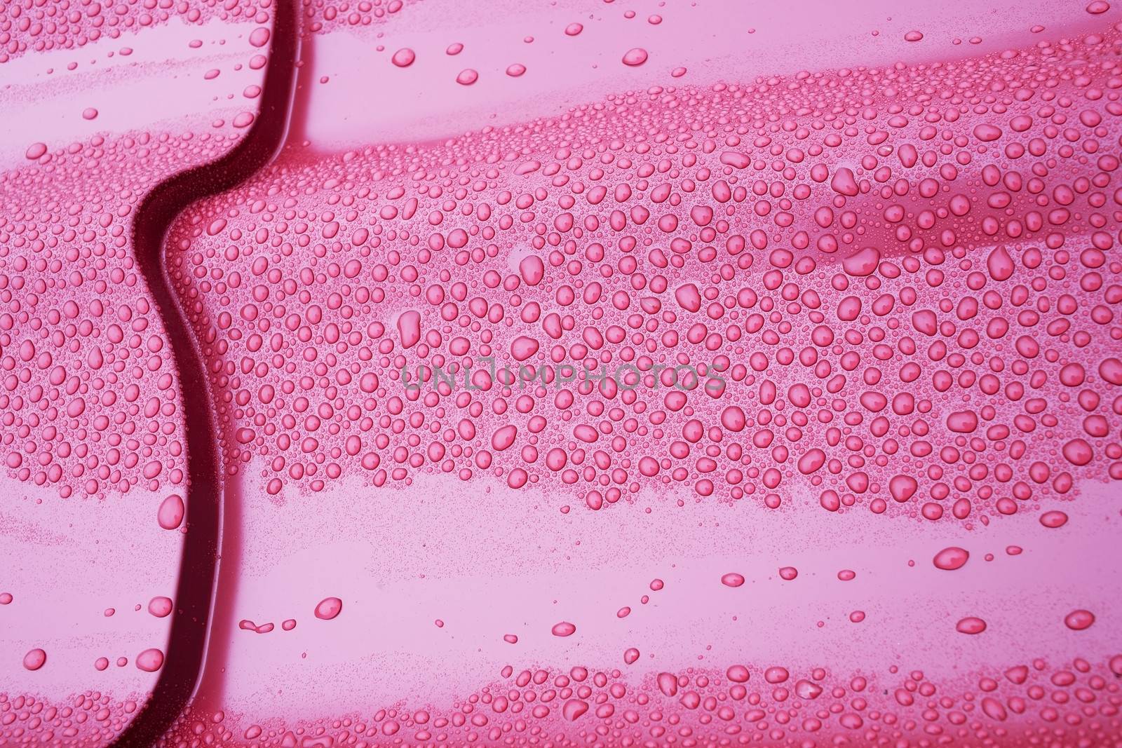 Drops of water on a metal tile red closeup