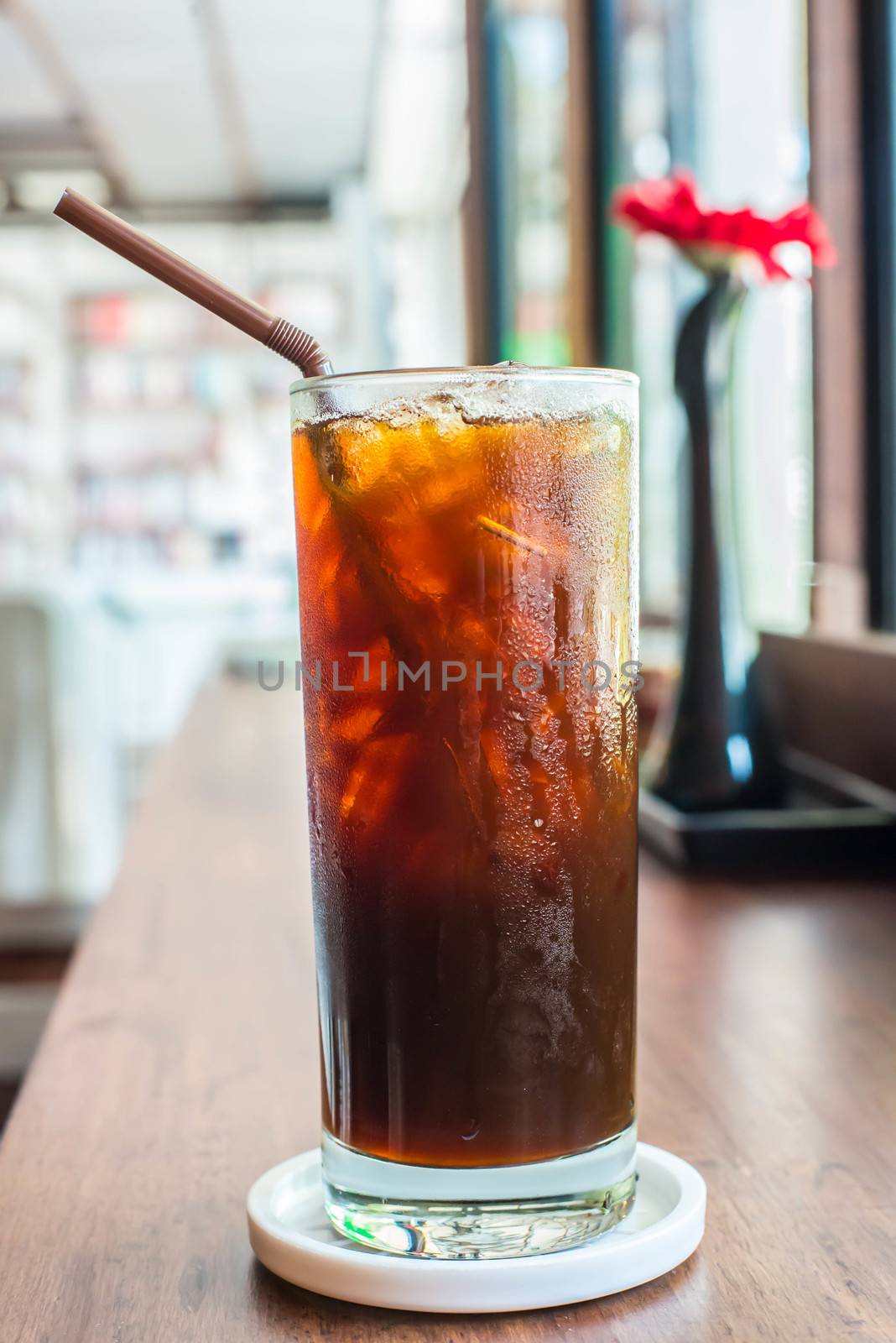 Iced black coffee on the wooden table in coffee cafe.