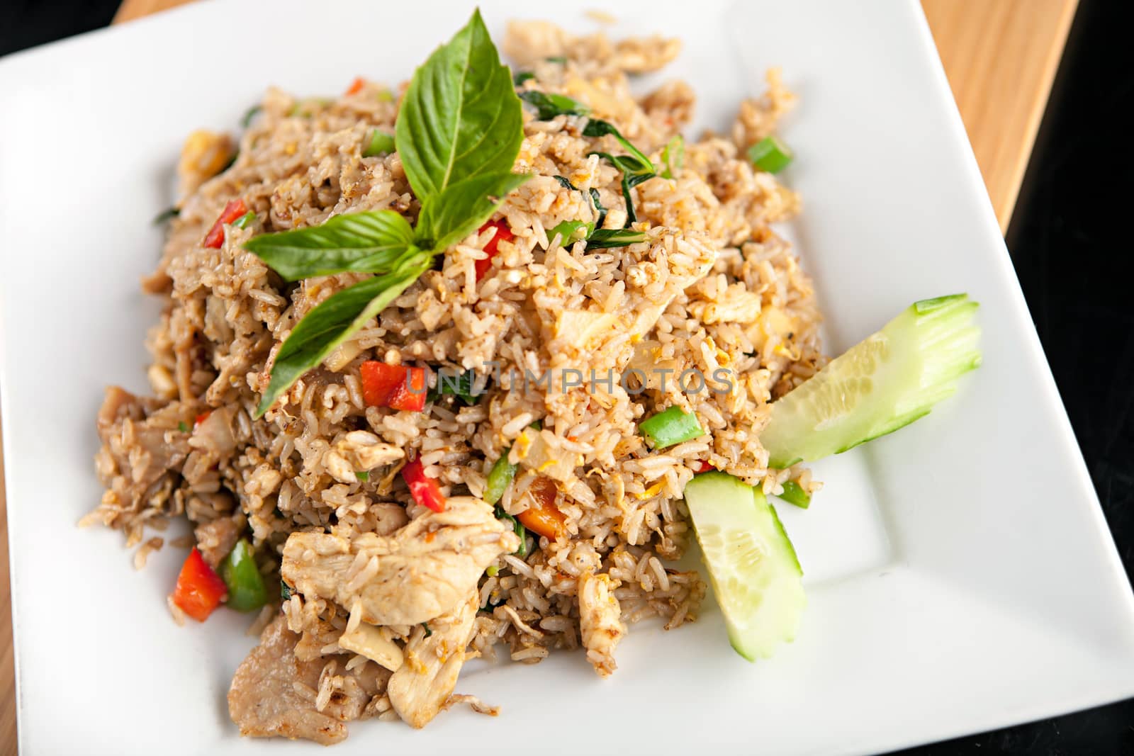 A Thai dish of chicken fried rice presented on a square white plate.