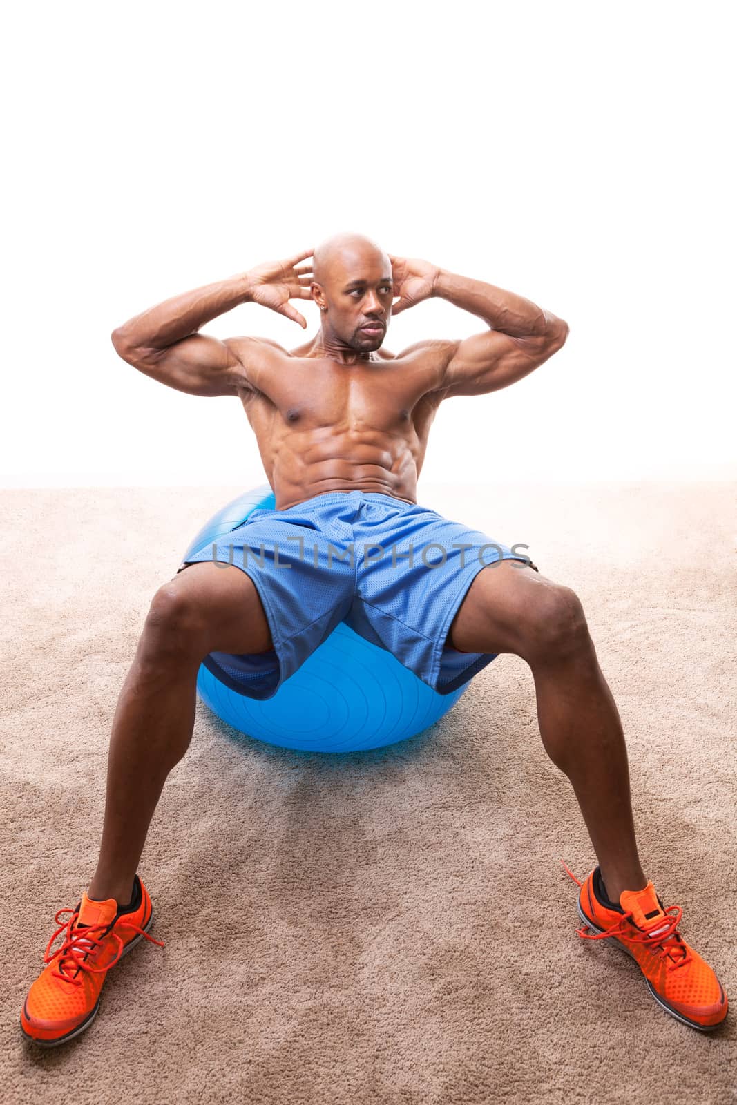 Muscular man doing ab crunches on an exercise ball.  