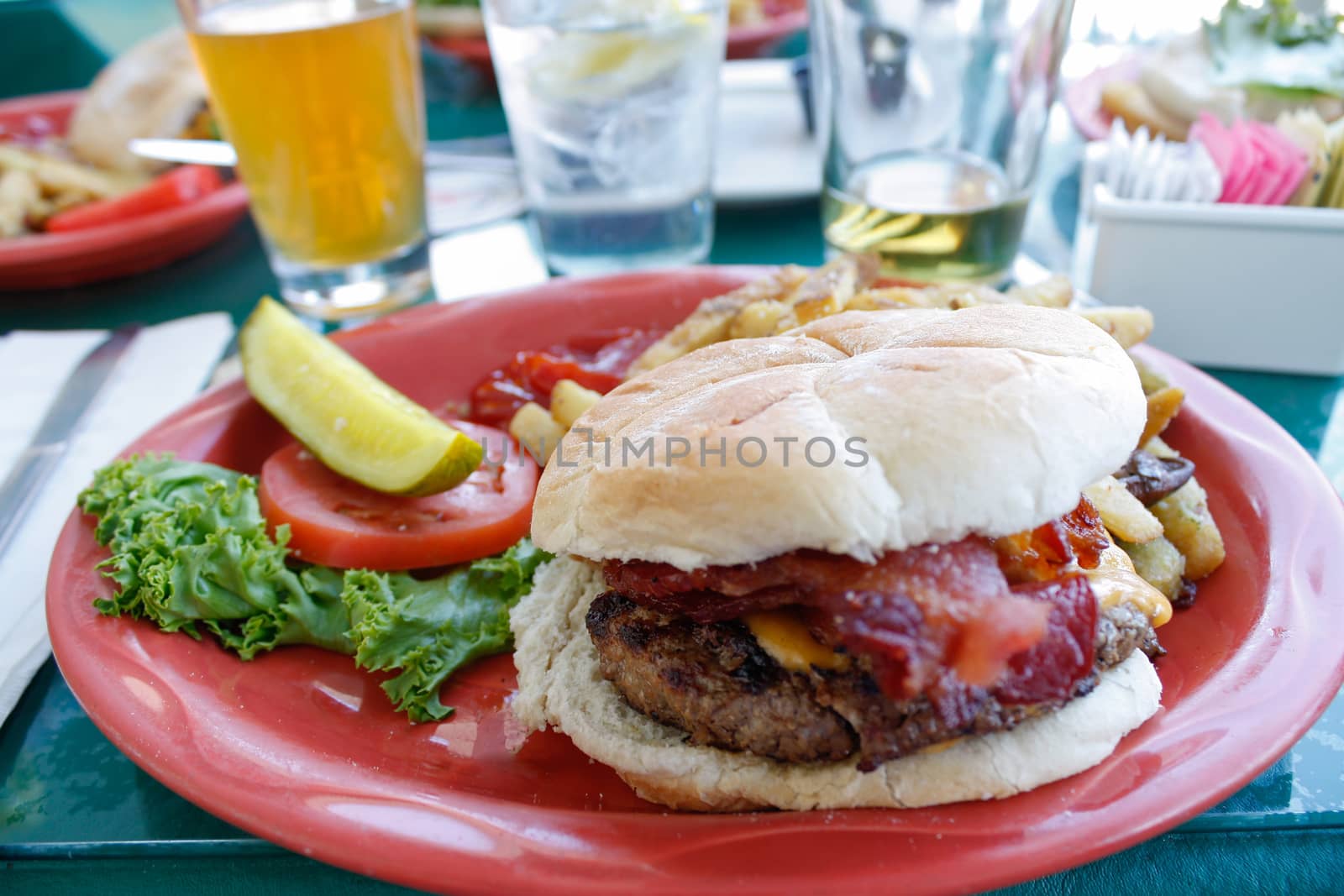 Gourmet burger with cheese mushrooms and thick cut bacon and a side of fries. Shallow depth of field.