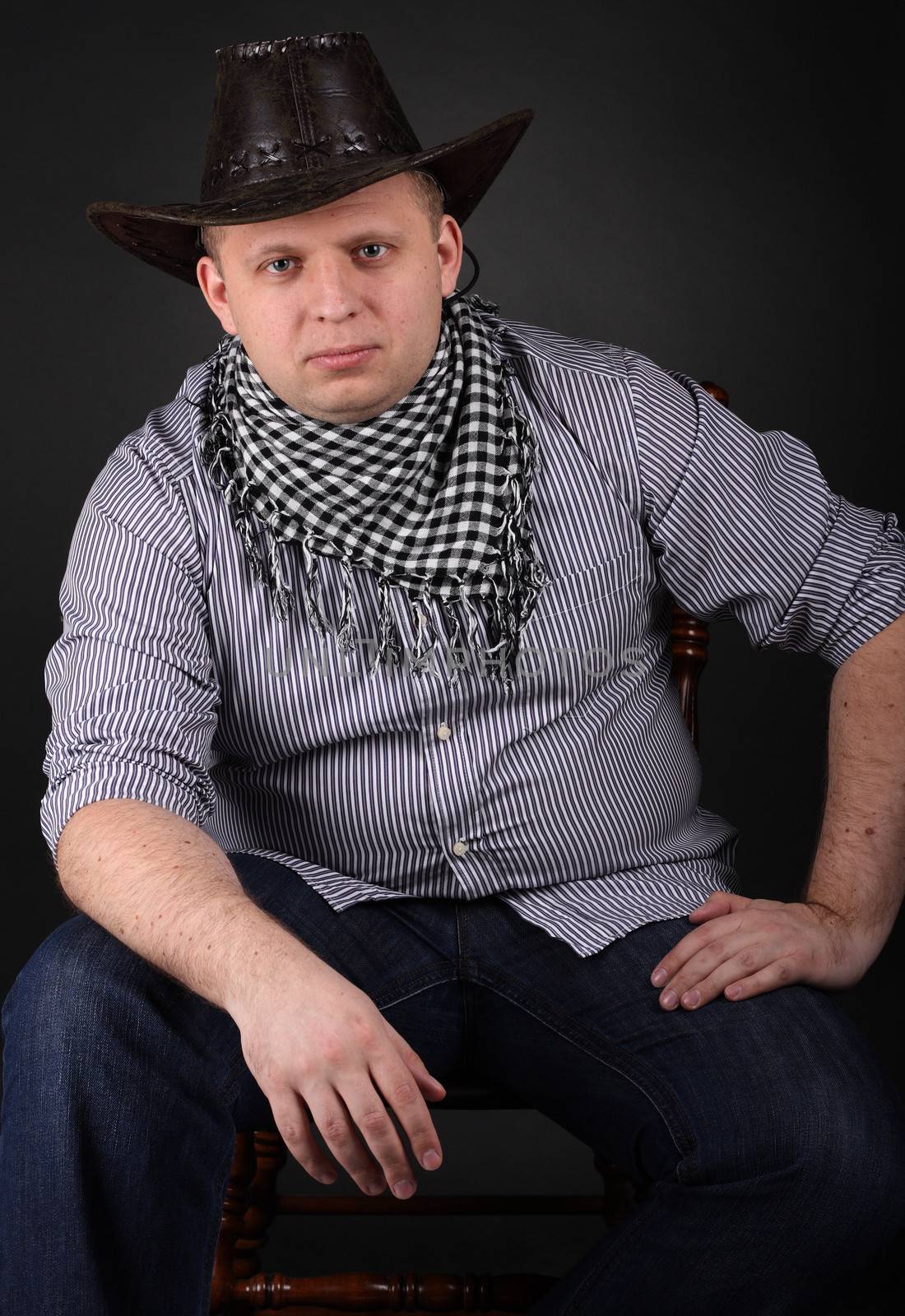 Man in a hat sitting on a chair at dark background