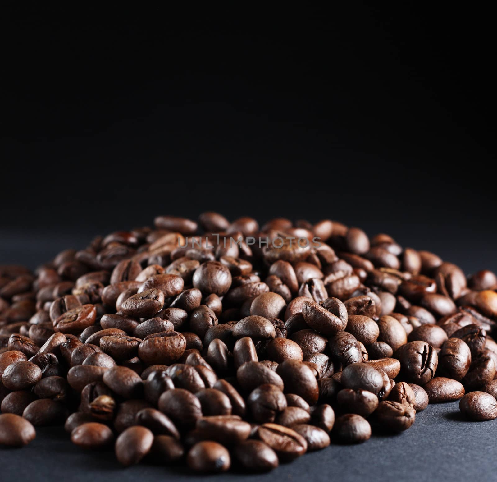 A lot of roasted coffee beans at dark background