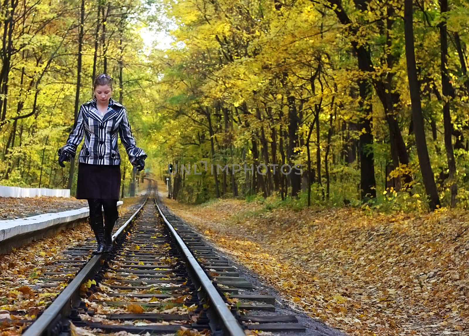 Young women walking on rails in a autumn park