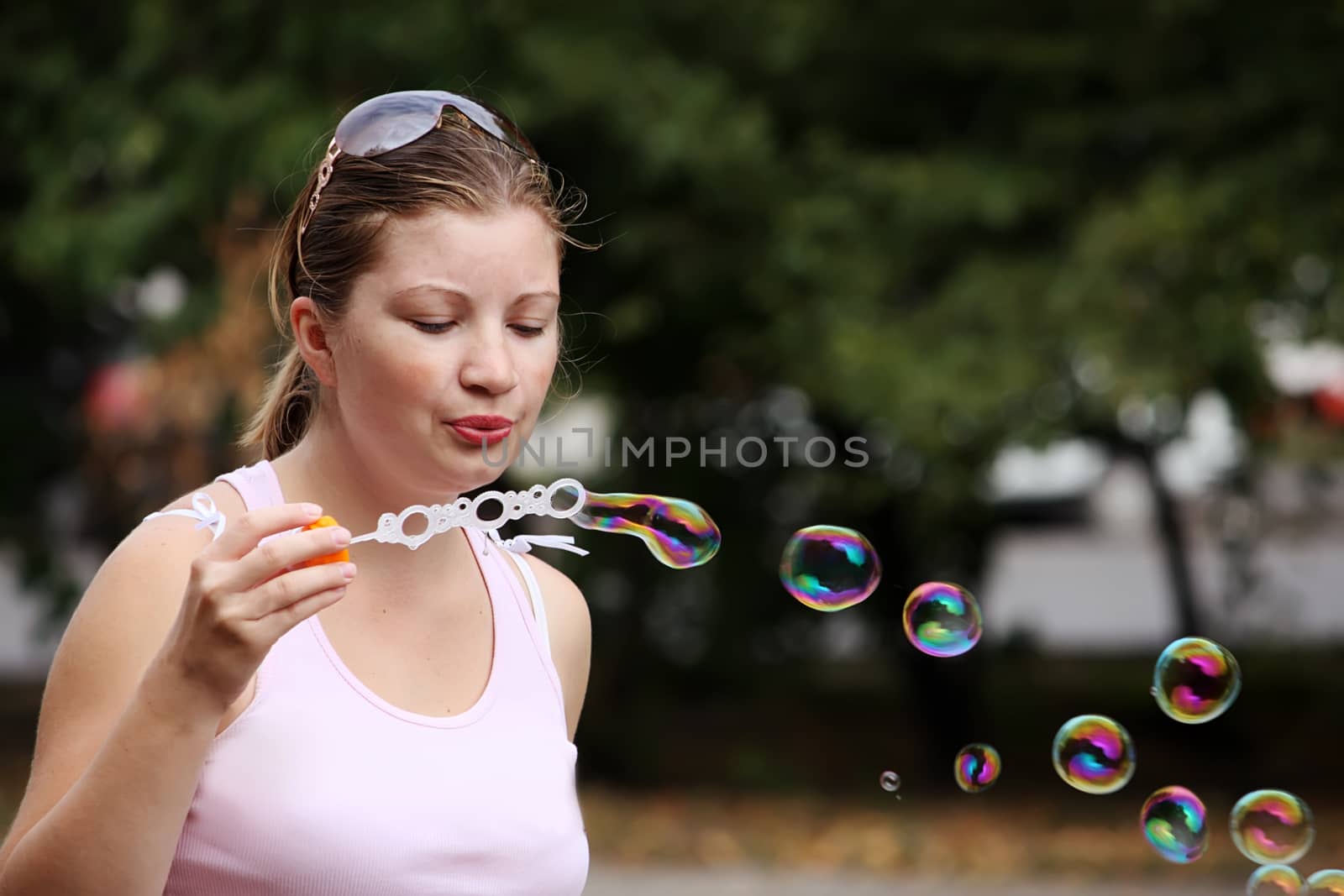 Yung woman blows bubbles in a city park