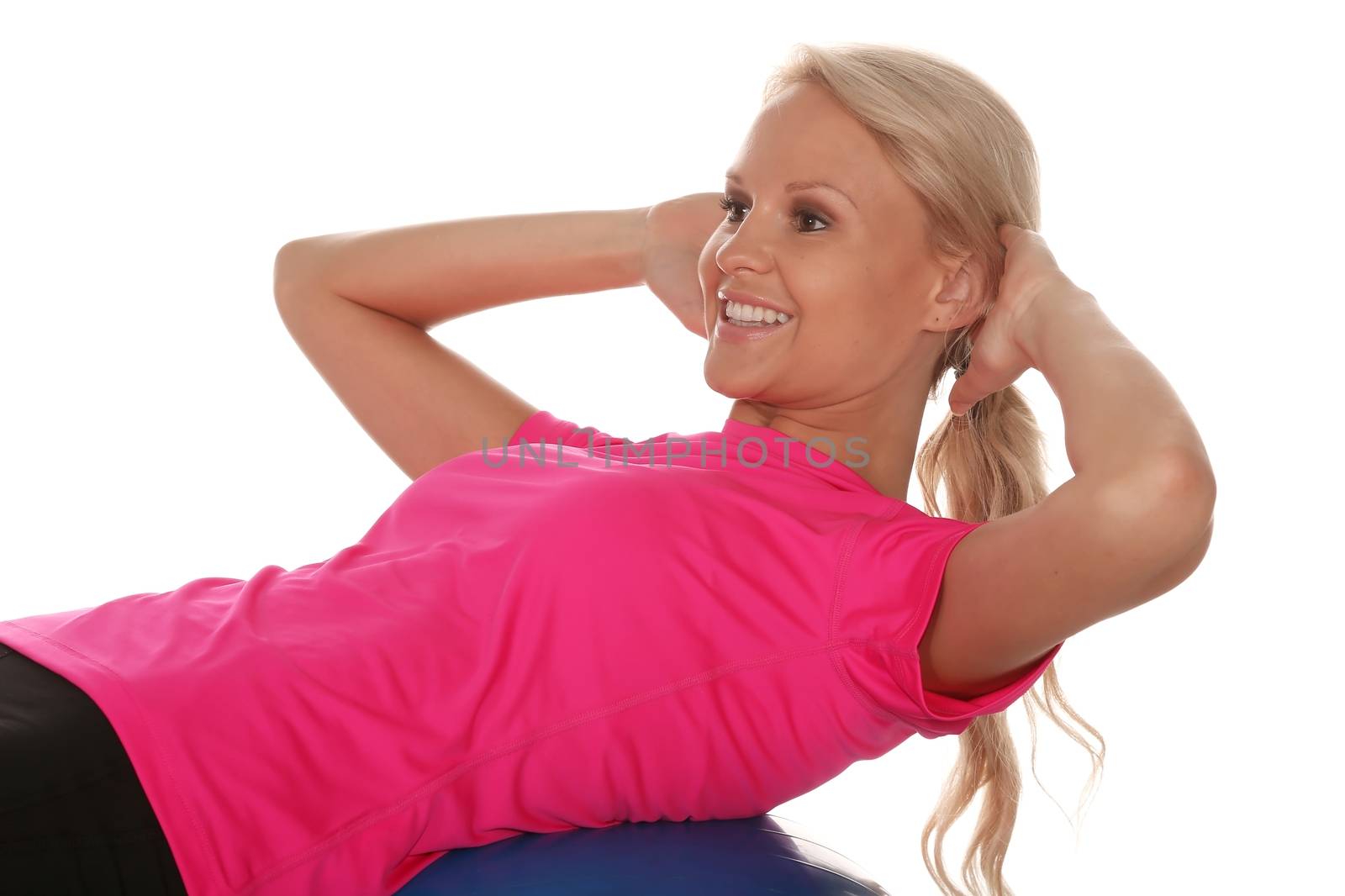 Beautiful young blond lady athlete doing sit ups on an exercise ball