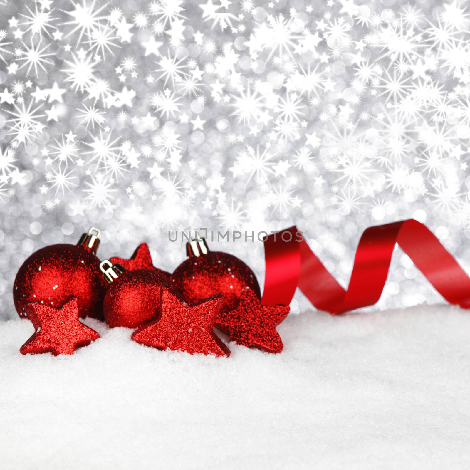 Shiny red christmas decoration on snow over silver glitter background