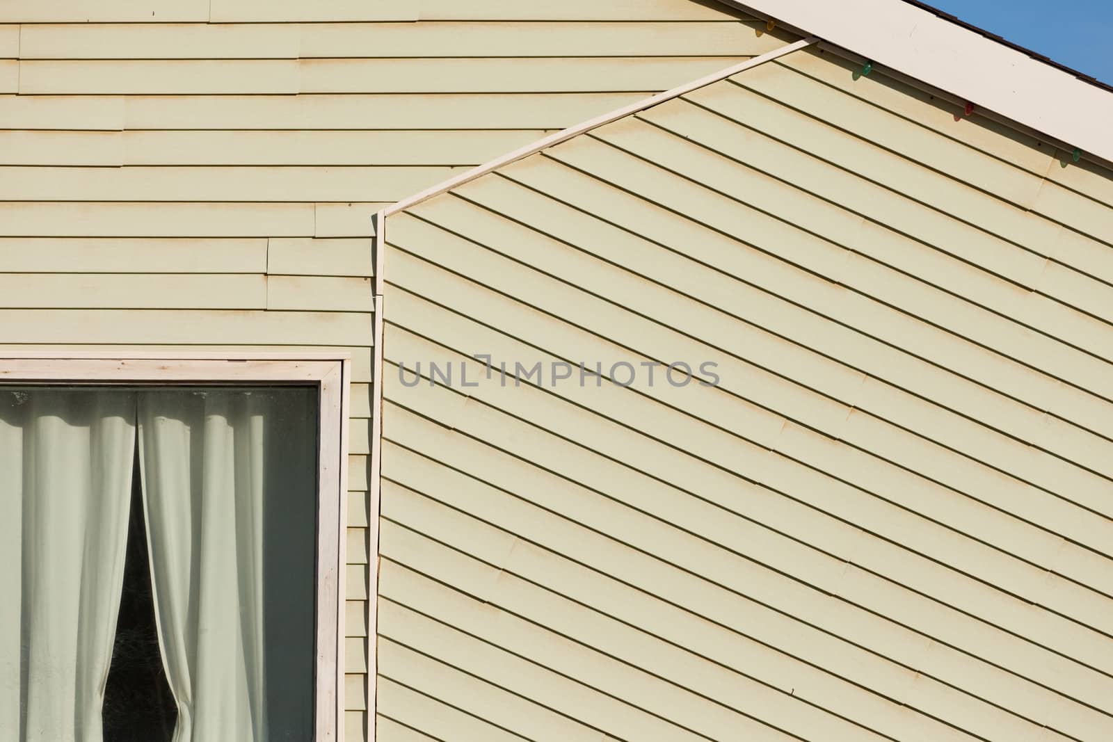 Exterior of a timber clad building architectural abstract showing a portion of a curtained window and the pitch of the roof with an angled segment of cladding following the facade