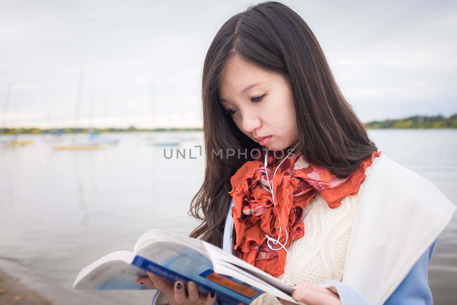 Girl reading book near lake by IVYPHOTOS
