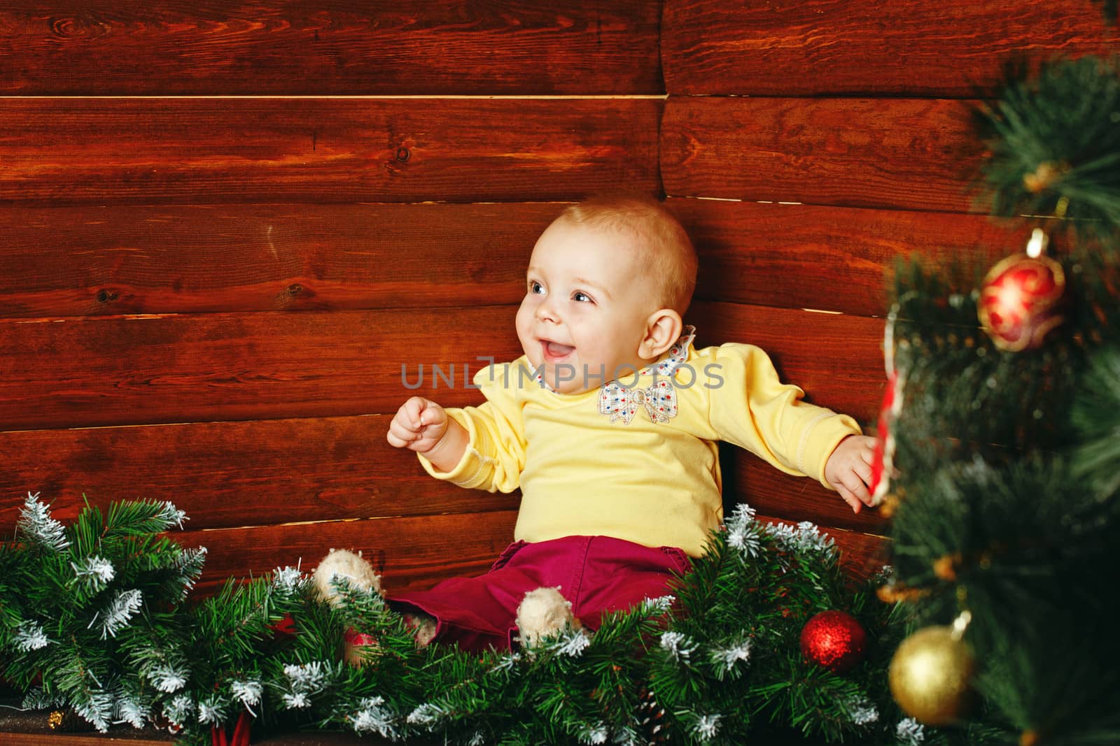 Red-haired and blue-eyed little girl and christmas tree decoration balls