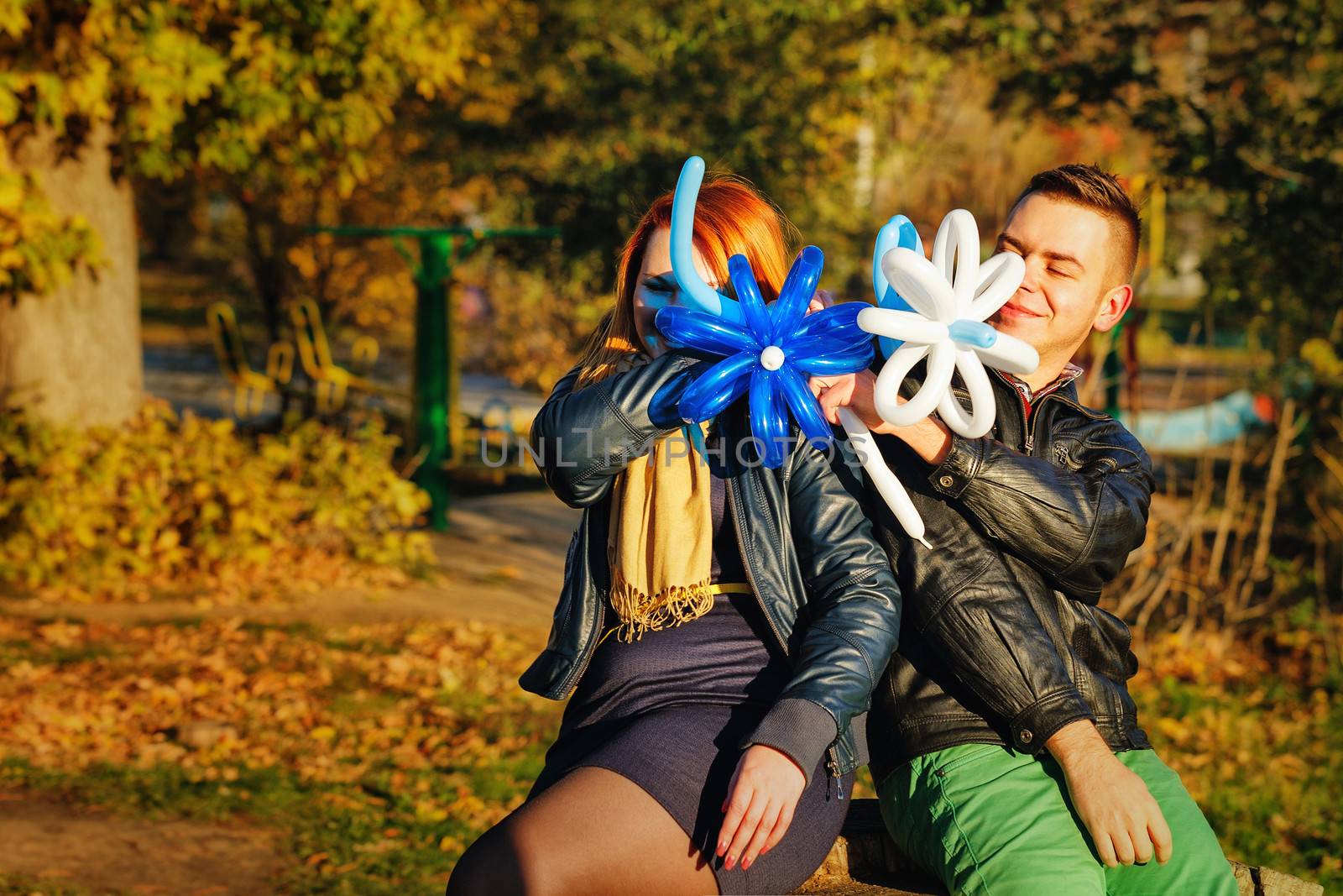 Couple playing with balloons in autumn park on a sunny day