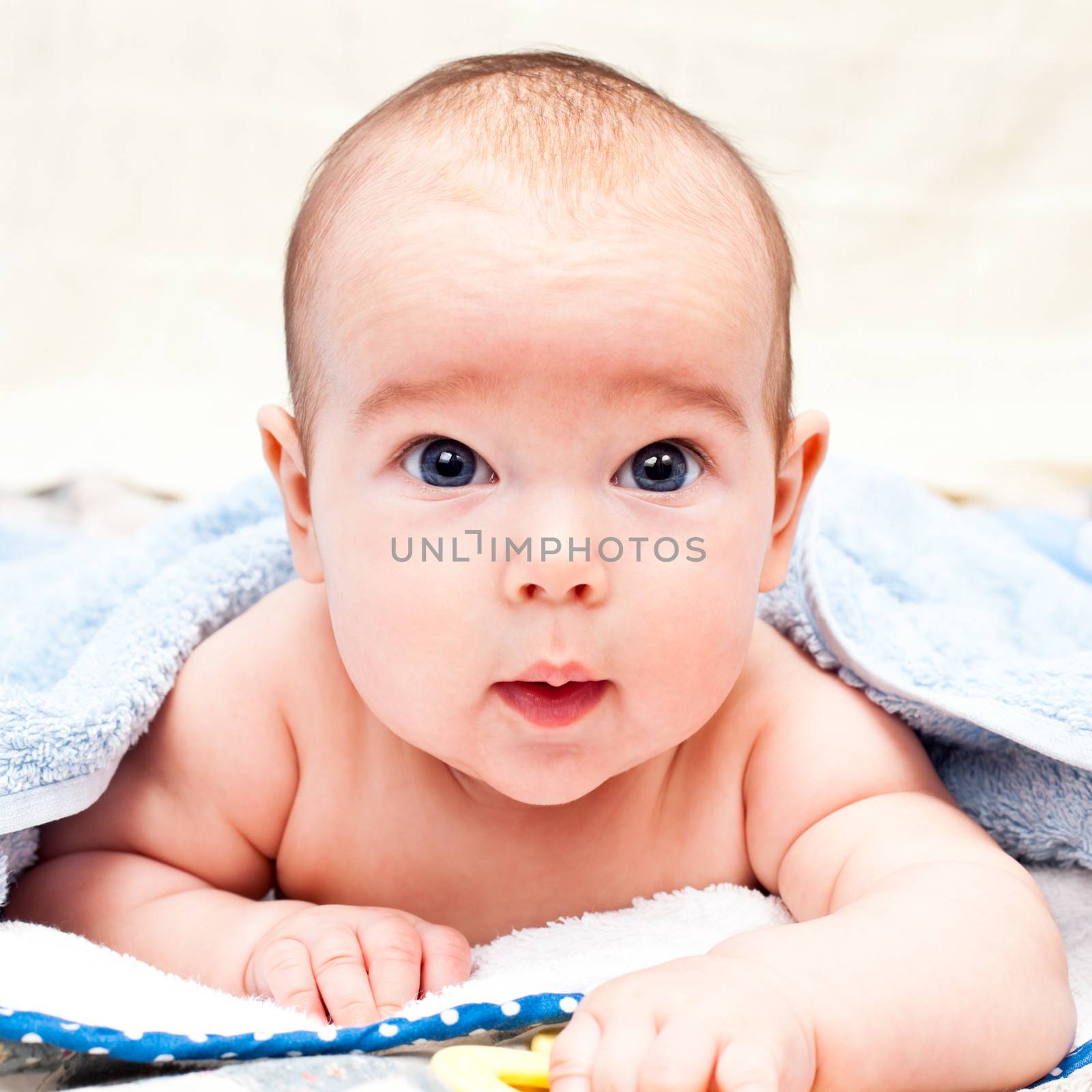 Little baby girl lying under towel