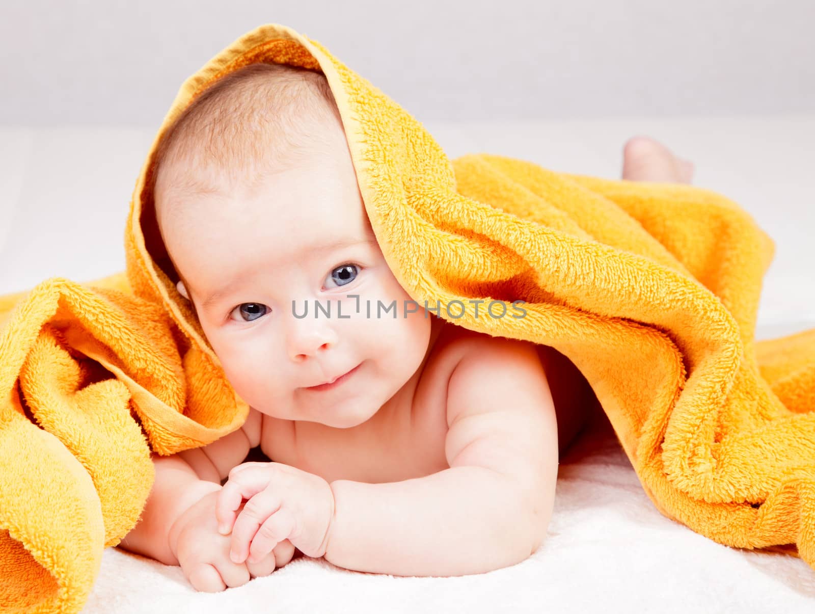 Little baby girl lying under yellow towel