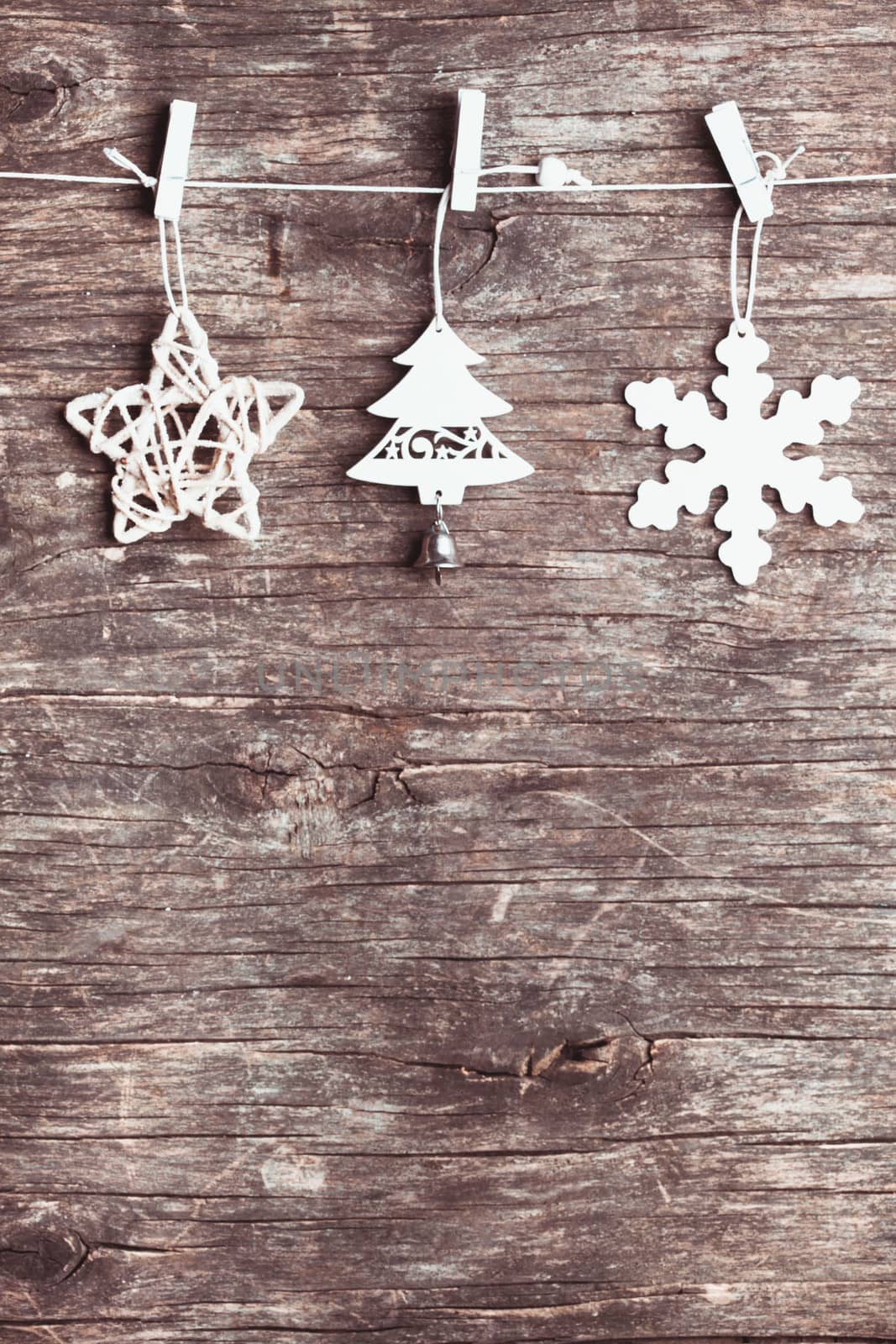 White christmas decorations attached to the rope, over wooden background