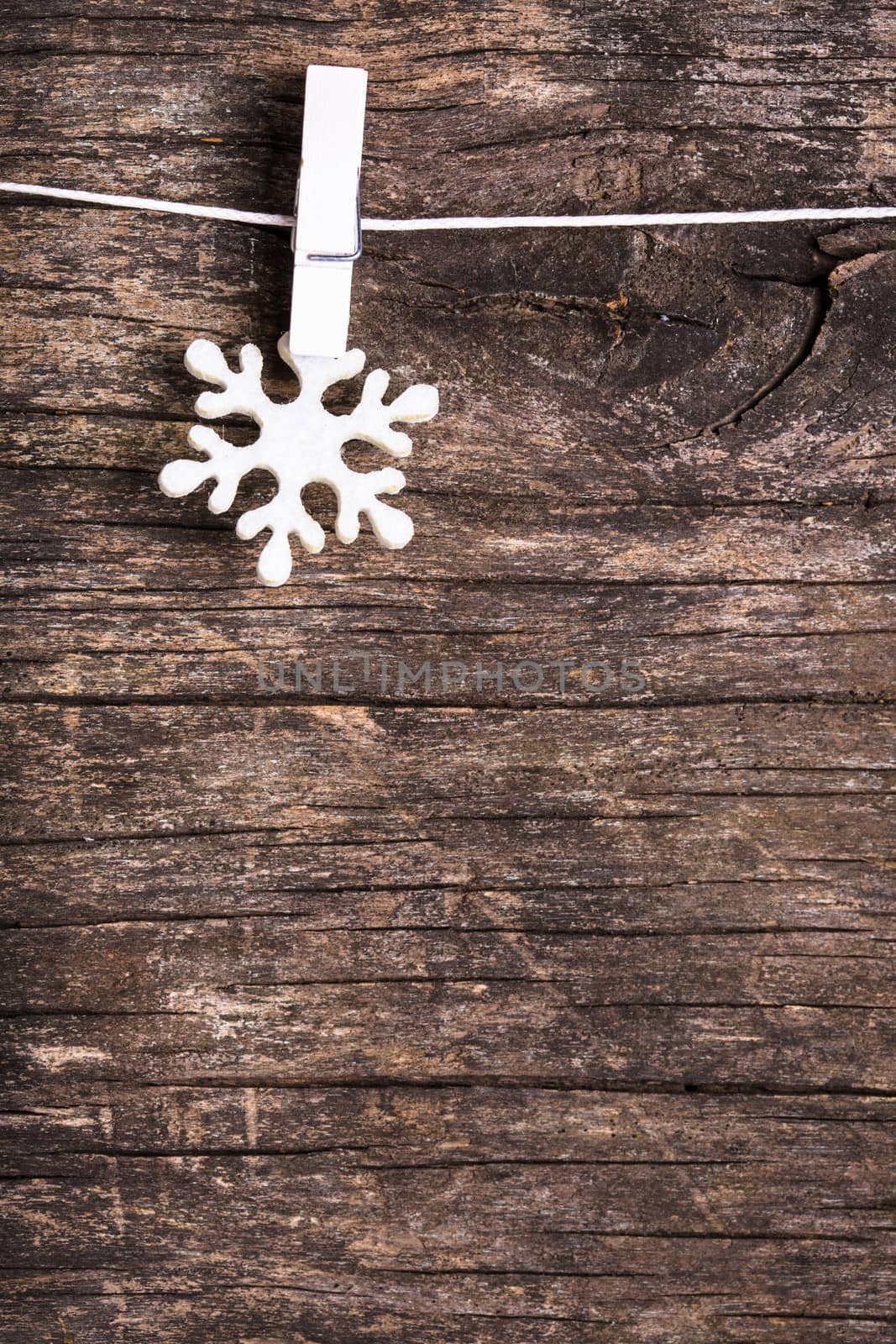 White snowflake decoration attached to the rope, over wooden background