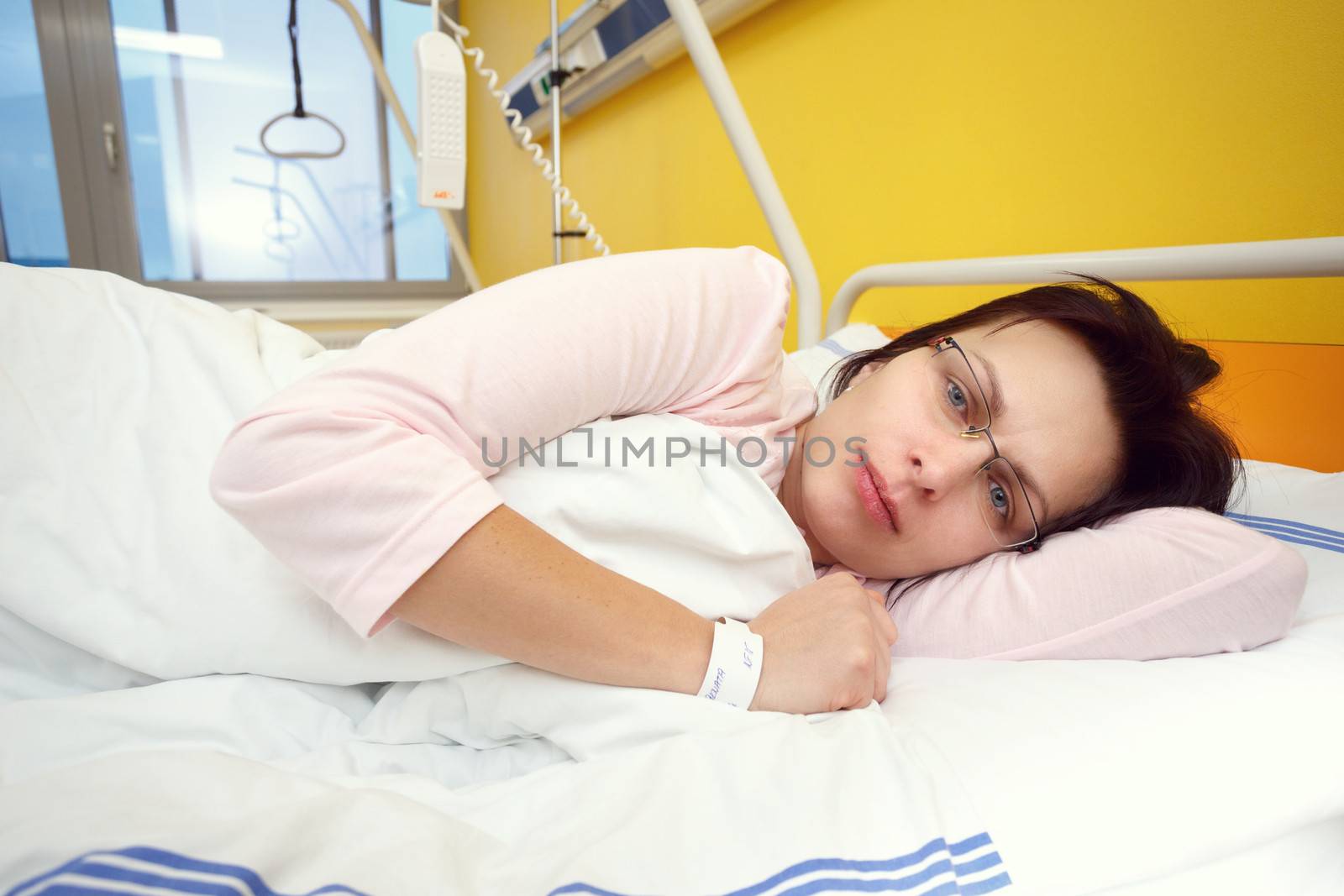 Real people in real situation, sad middle-aged woman lying in hospital with pneumonia