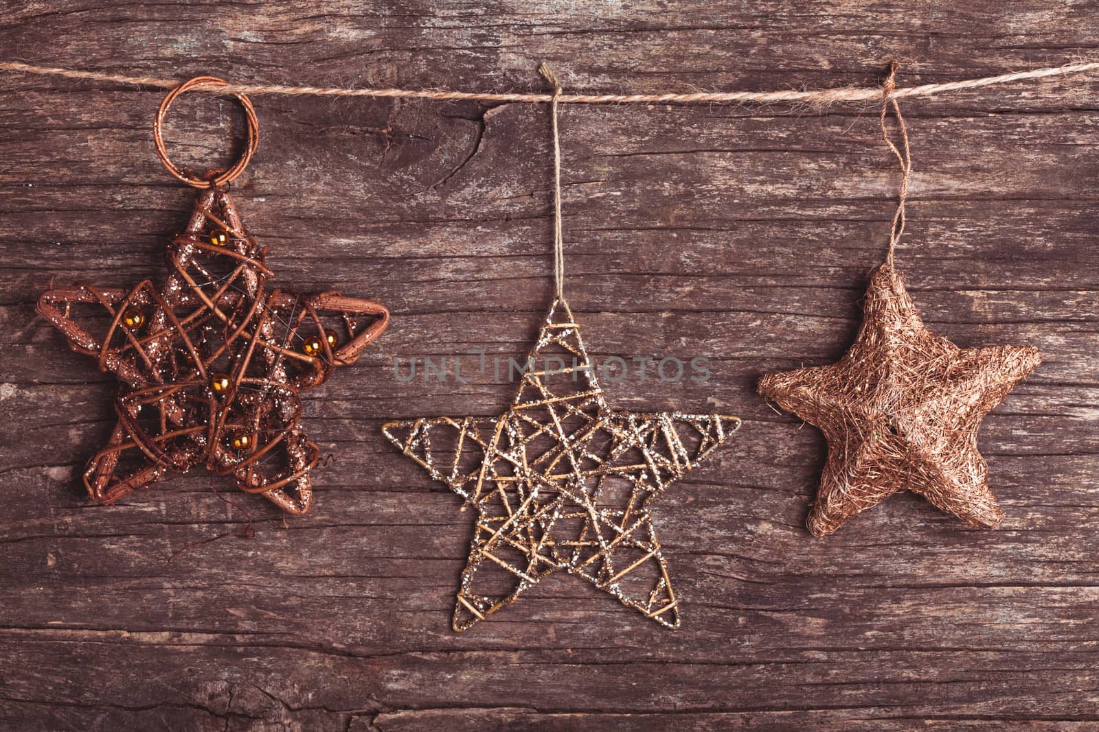 Brown christmas decorations attached to the rope, over wooden background