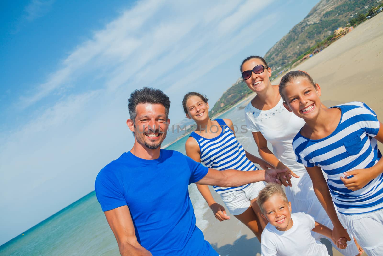 Photo of happy family with three kids running down the beach