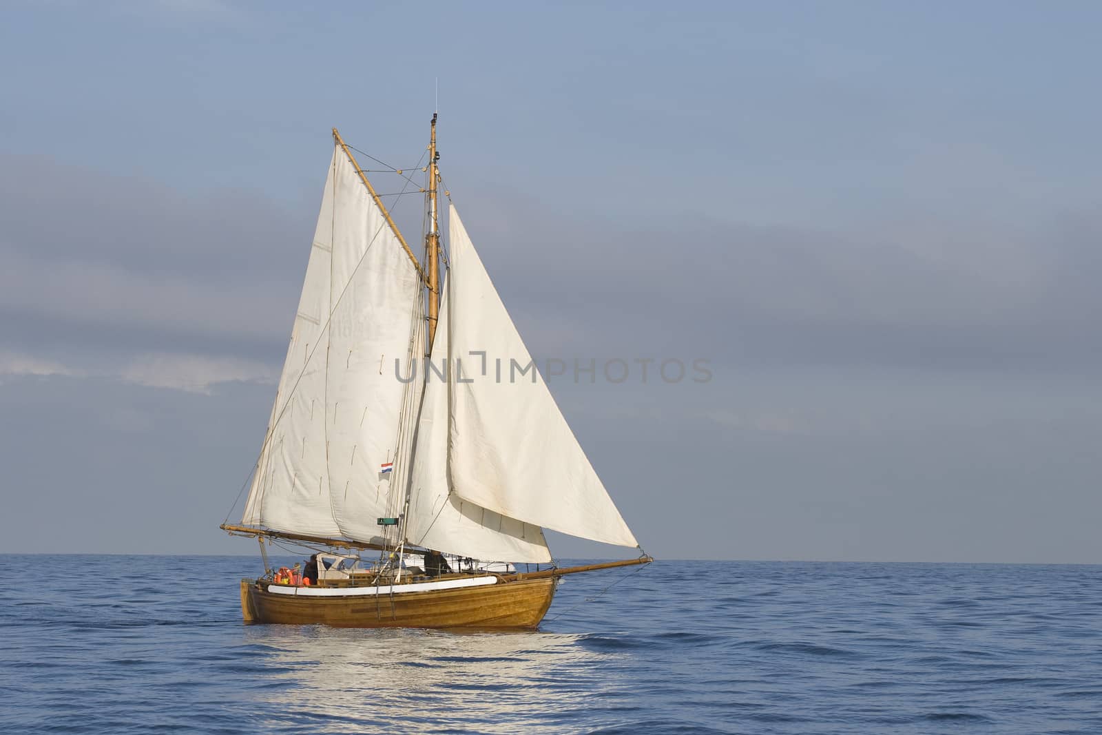 Tender with white sails in the calm sea