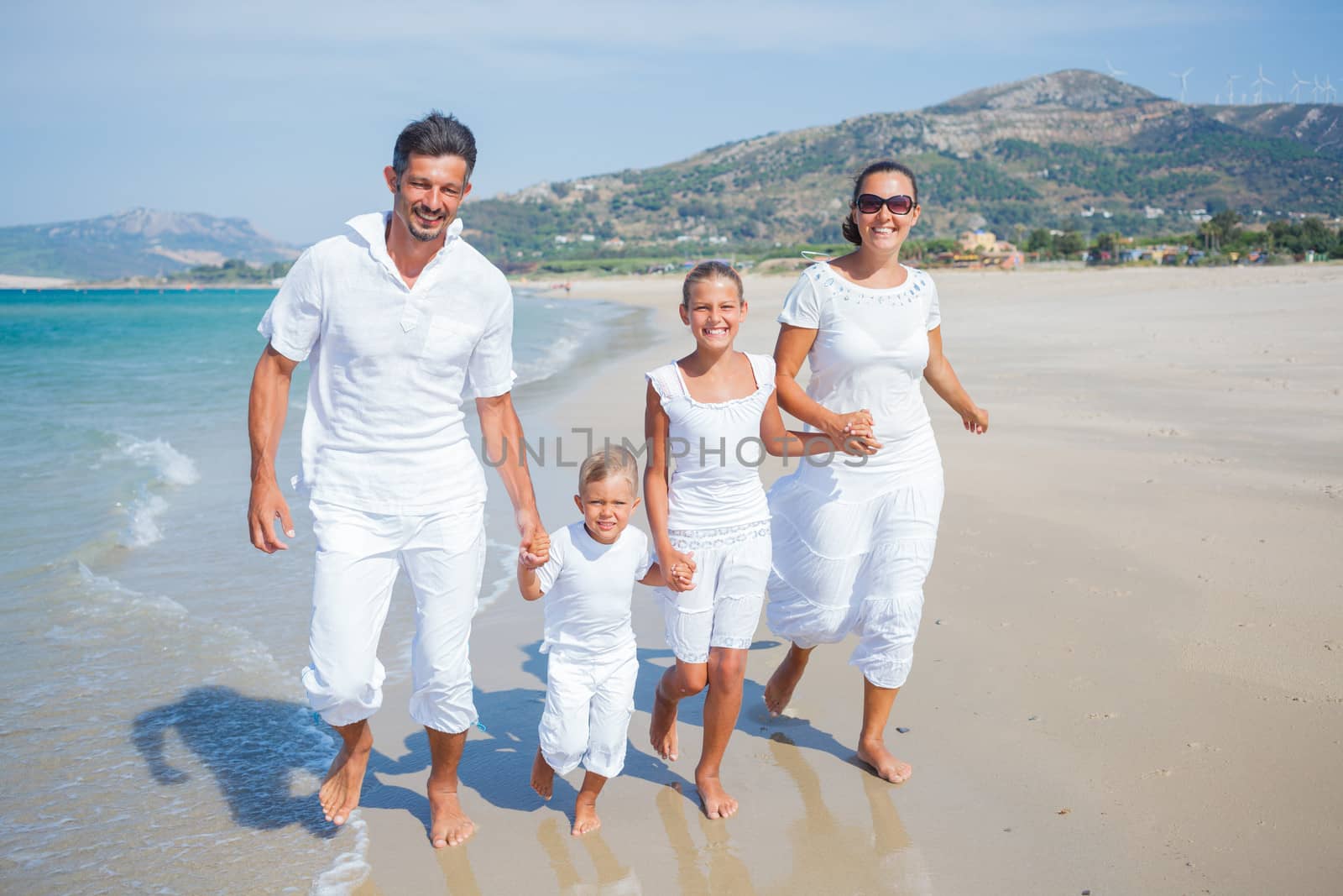 Photo of happy family running on the beach