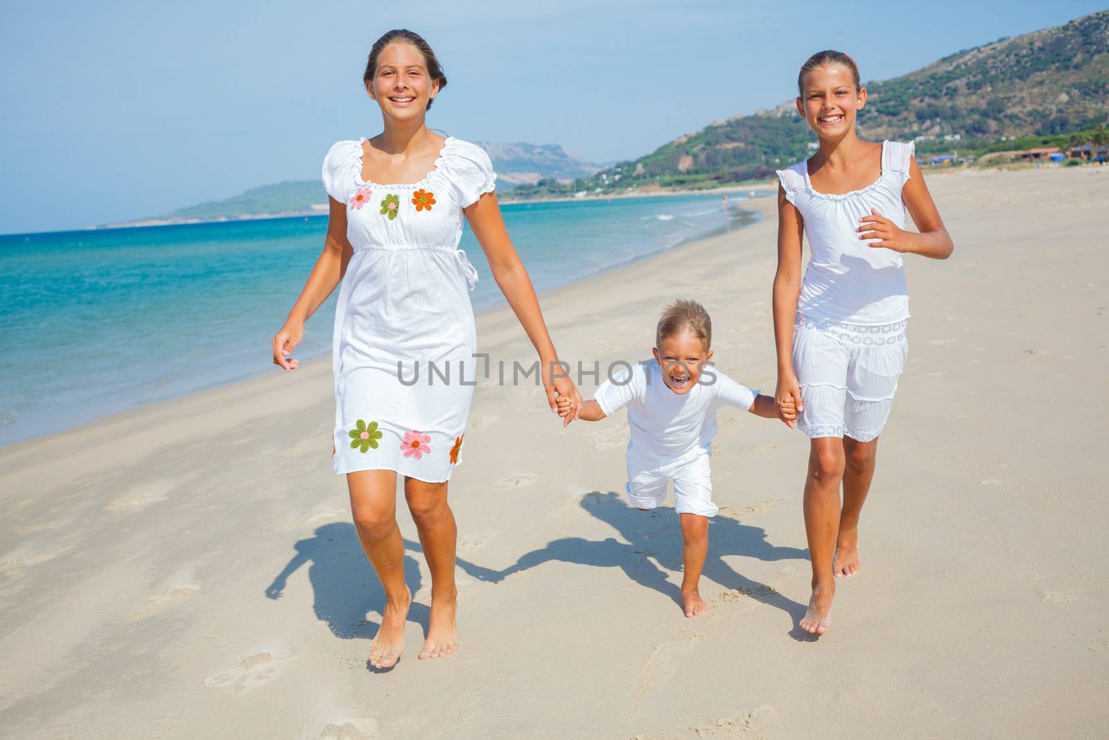 Adorable happy boy and girls running on beach vacation