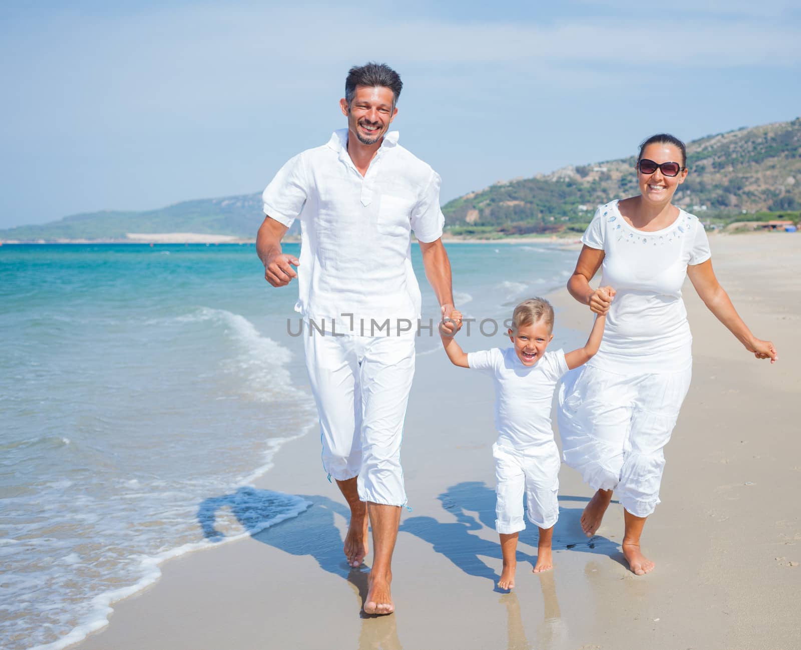 Photo of happy family running on the beach