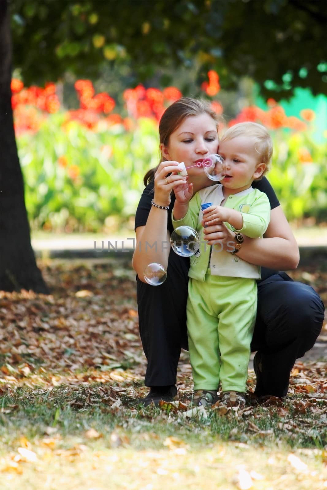 Young woman with her son blows bubbles in a city park