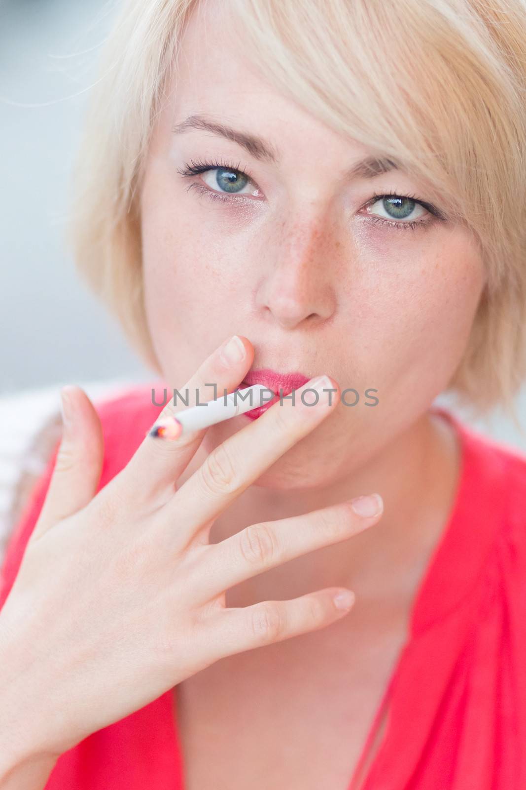 Young tobacco addicted woman smoking a cigarette.