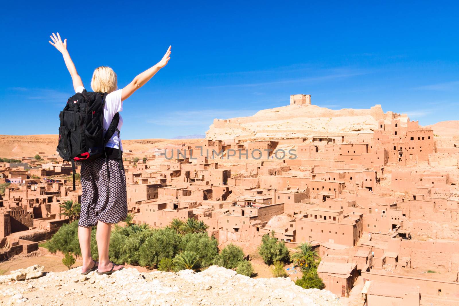 Traveler arms reised in front of Ait Benhaddou, Morocco. by kasto