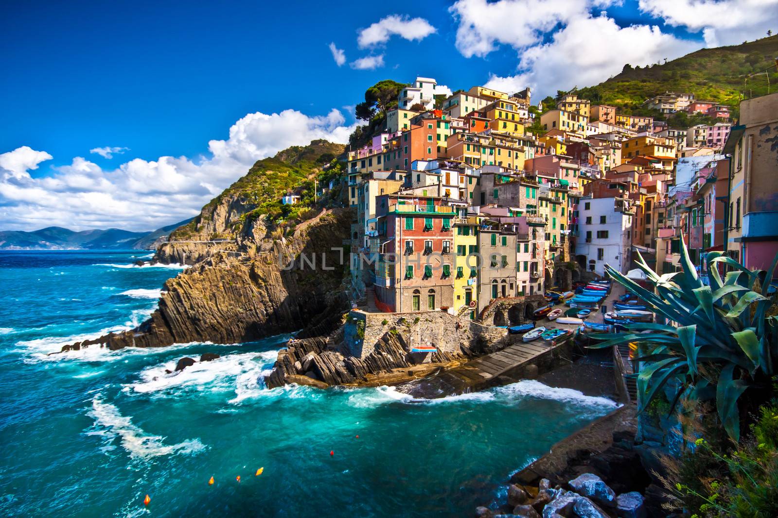 Riomaggiore fisherman village in a dramatic windy weather. Riomaggiore is one of five famous colorful villages of Cinque Terre in Italy, suspended between sea and land on sheer cliffs upon the  turquoise sea.