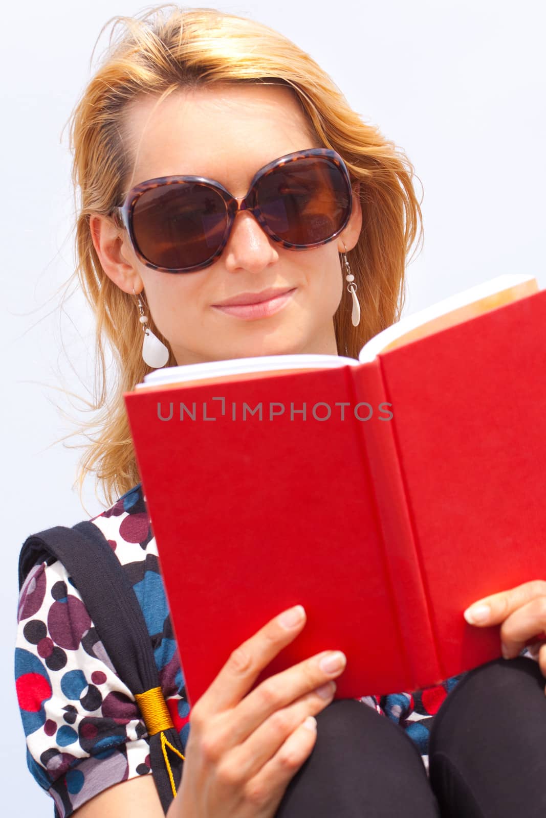 Attractive young lady reading a book by the sea.